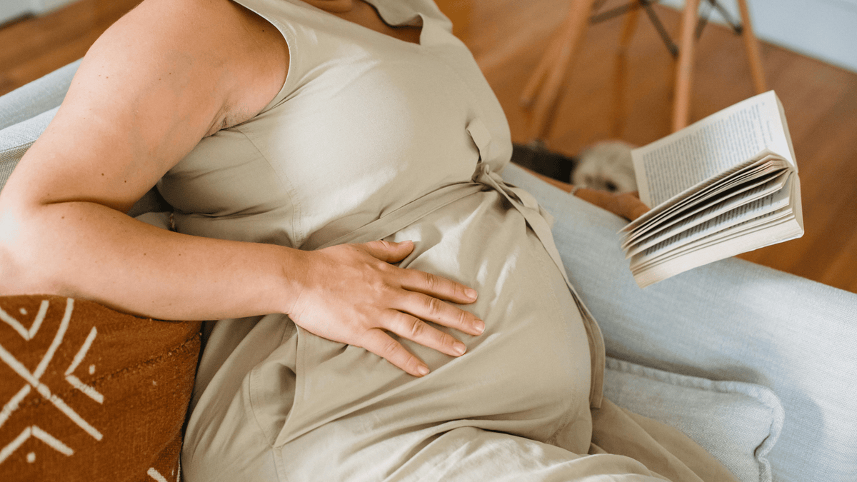 A pregnant woman comfortably reading childbirth book at home