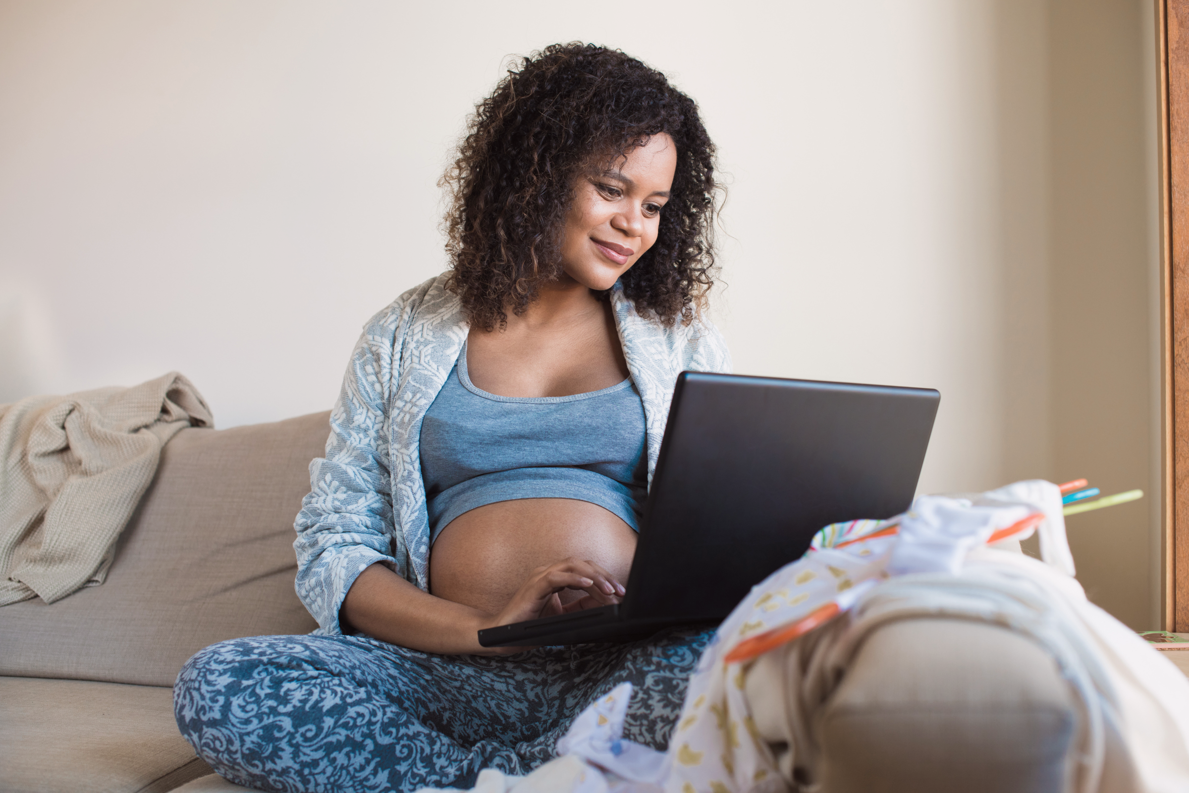 Woman on sofa researching best online childbirth classes on her laptop