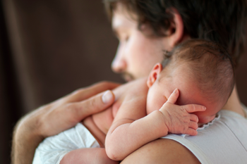 Sleepy dad holding newborn who looks tired too