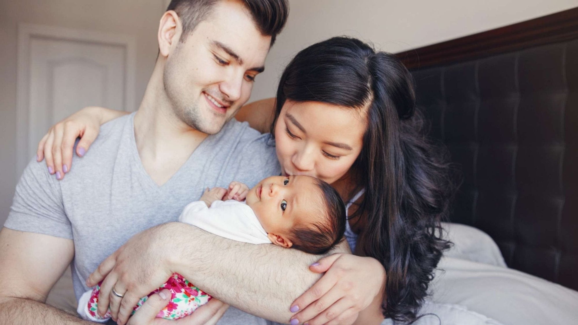 Smiling couple holding their newborn together, showing love, teamwork, and shared responsibility in early parenthood