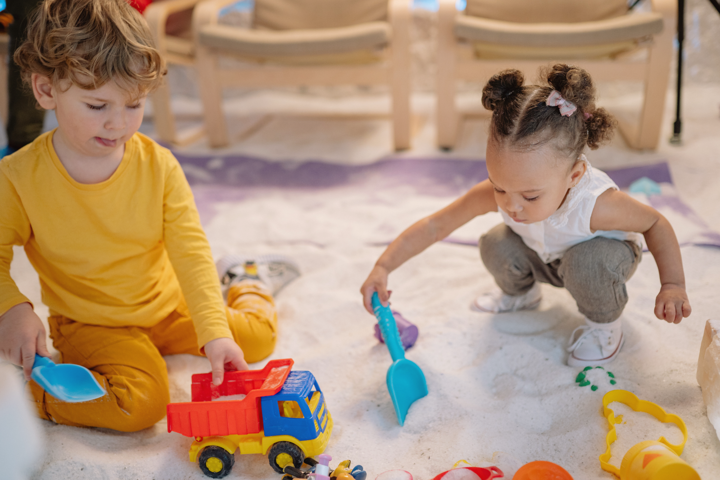 Toddlers playing with sand toys, one of the best toys for babies 0–2 that supports sensorimotor development