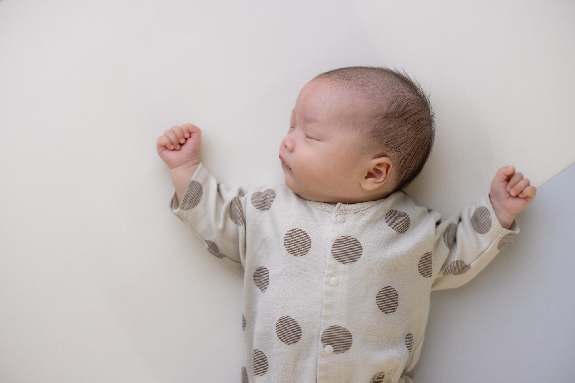 Newborn sleeping comfortably on a white surface, illustrating newborn sleep schedule by week.