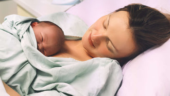 A mother enjoying skin to skin after birth with her newborn wrapped in a blanket.