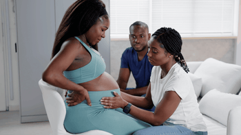 Pregnant woman practicing labor positions with support from a doula and partner in a hospital setting