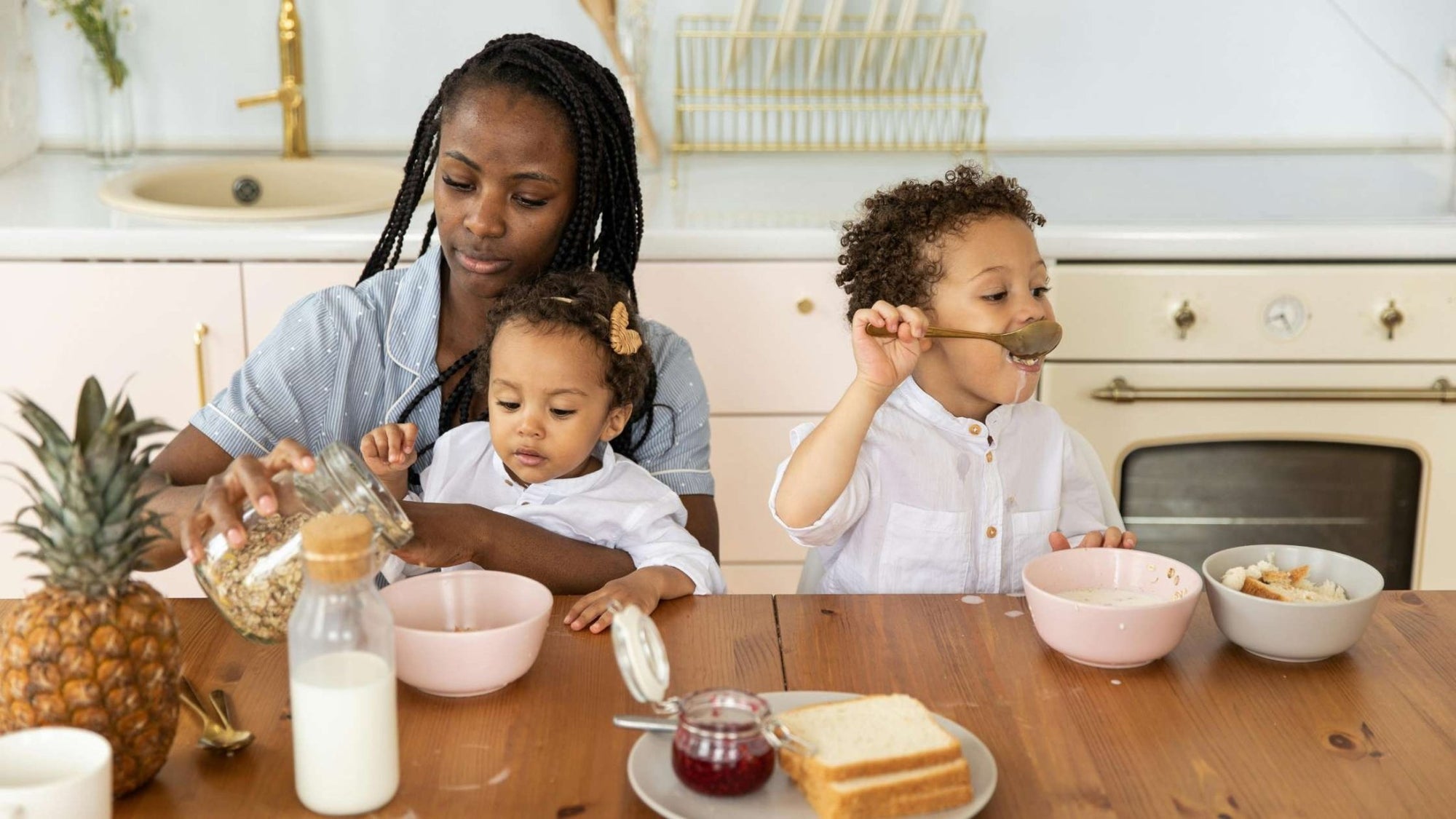 Parent serving breakfast to two young children, supporting early eating skills and mealtime routines
